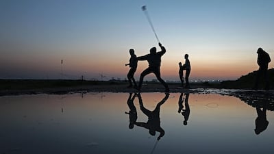 A protester throws stones at Israeli troops, as sun sets during clashes near the border between Israel and east Gaza Strip. Mohammed Saber / EPA