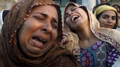 Relatives grieve upon seeing a body of a victim, that was pulled from the rubble of a landslide in the Gulistan-i-Jauhar area, in an ambulance in Karachi. Athar Hussain / Reuters