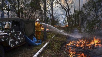 A firefighter sprays water onto a small fire burning near a home in western Sydney. The fires threaten to worsen in coming days. Reuters