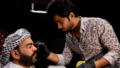 Iraqi actor Ayad al-Atabi, (L), gets his makeup done on the set of a parody sketch video of Bab al-Hara, an adaptation of an iconic long-running Syrian television drama, in Iraq's southern port city of Basra on April 22, 2020. AFP / Hussein Faleh