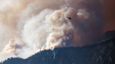 A helicopter prepares to make a water drop as smoke billows along the Fraser River Valley near Lytton, British Columbia, Canada, on Friday, July 2, 2021. Bloomberg