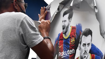 A worker removes posters featuring Argentinian forward Lionel Messi at Camp Nou.
