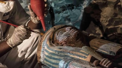 Restoring ancient treasures: an Egyptian archaeologist workin on a wooden sacrophagus on September 9, 2017, at a newly-discovered ancient tomb for a goldsmith on the west bank of the Nile at Luxor. Khaled Desouki / AFP