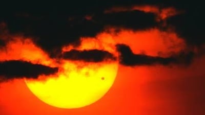 A file picture taken on June 8, 2004 shows the sun rising through clouds over a bridge on the East River of Manhattan, as the planet Venus (dot on lower right of sun) crosses its face, in New York.