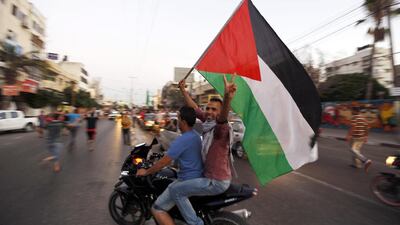 Palestinians wave the national flag as they gather is the streets of Gaza City on August 26, 2014, to celebrate a long-term truce agreed between Israel and Hamas in the Gaza Strip. Mohammed Abed / AFP