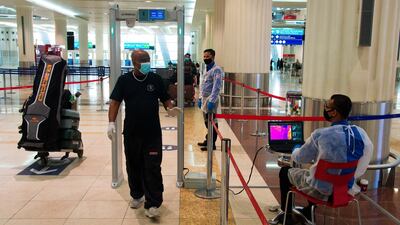 A passenger wearing a mask passes through a temperature screening at Dubai International Airport's Terminal 3 in Dubai. The coronavirus pandemic has hit global aviation hard, particularly at Dubai International Airport, the world's busiest for international travel, because of restrictions put in place to contain the virus. AP Photo
