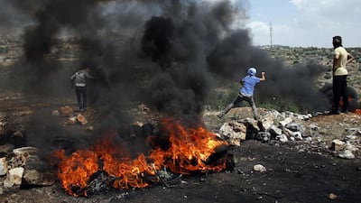A Palestinian protester throws stones towards Israeli security forces during clashes following a weekly protest against the expropriation of Palestinian land by Israel in the West Bank village of Kfar Qaddum, near Nablus. Thomas Coex / AFP