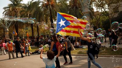 A woman carries an Estelada (Catalan separatist flag) past a child playing with soap bubbles during a protest outside the High Court of Justice of Catalonia in Barcelona, Spain, September 21, 2017. REUTERS/Jon Nazca