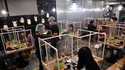 People eat in between plastic partitions at the Penguin Eat Shabu hotpot restaurant in Bangkok. AFP