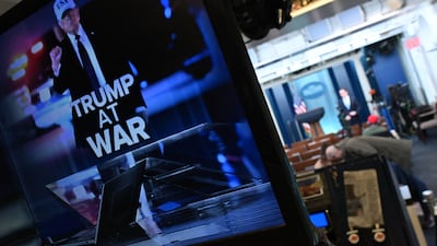 Reporters are seen in the briefing room near a television monitor displaying an illustration reading 'Trump at War' alongside a photo of US President Donald Trump at the White House. AFP