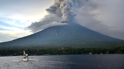 A fisherman drives a traditional boat as Mount Agung erupts, as seen from Kubu sub-district in Karangasem Regency on Indonesia's resort island of Bali on November 28, 2017. Sonny Tumbelaka / AFP