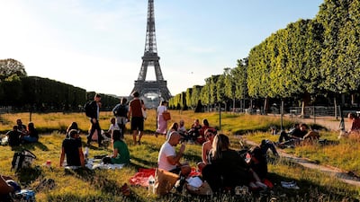 People sit on the Champs de Mars at sunset in front of the Eiffel Tower, May 17, Paris, on the first weekend after France eased lockdown measures taken to curb the spread of Covid-19. Ludovic Marin / AFP