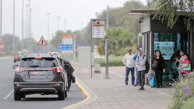 Commuters seek refuge from the rain beneath a bus shelter in Abu Dhabi. Victor Besa / The National