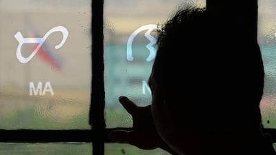 This photo taken on July 15, 2019 shows National Museum researcher Leo Batoon pointing to a Baybayin character etched on a glass window at the National Museum in Manila. From tattoos, shirts, and artworks to a computer font and mobile apps, Baybayin found a rebirth among millennials and professionals learning its 17 characters beyond the marginal mention in history class.