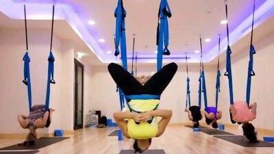 Pilar Sanchez, centre, instructs a class on how to invert using slings at Fitness First's yoga studio in Dubai Motor City. Razan Alzayani / The National