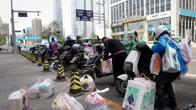Delivery riders load packages for distribution in Beijing. EPA