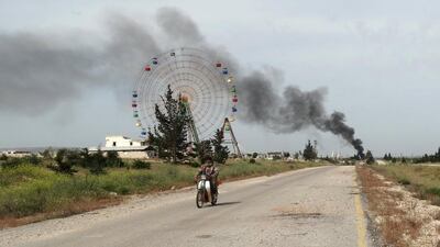 A rebel fighter rides a motorbike along a road in Qarmeed camp, as smoke rises in the background, after Islamist rebel fighters took control of the area from forces of Syria's President Bashar al-Assad. Abdalghne Karoof / Reuters