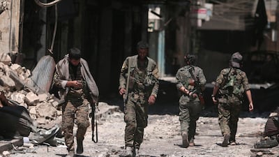 Syria Democratic Forces (SDF) fighters walk on the rubble of damaged shops and buildings in the city of Manbij. Reuters