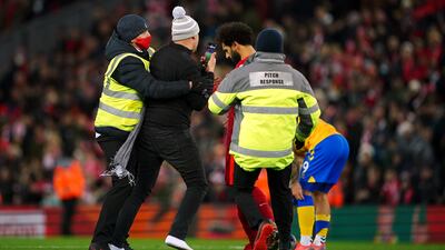 A pitch invader approaches Liverpool's Mohamed Salah after the Premier League match at Anfield, Liverpool.