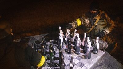 Members of a Territorial Defence unit play checkers with Molotov cocktails while guarding a barricade on the outskirts of Kyiv. Getty Images