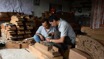 Nepalese woodcarver Indra Kaji Shilpakar, right, teaches his son Indra Prasad Shilpakar at his workshop in Bhaktapur. Prakash Mathema / AFP