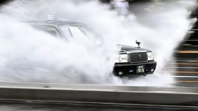 A taxi speeds through water covering a road in the Aoyama district of Tokyo, as the effects of Typhoon Hagibis is started to be felt in Japan's capital. AFP