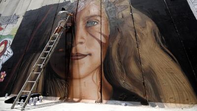 A foreign artist paints a mural of Palestinian Ahed Tamimi on the Israeli separation wall in the West Bank city of Bethlehem, 25 July 2018. EPA