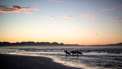 Surfers brave the cold waters at sunrise in Muizenberg, Cape Town, South Africa. AFP