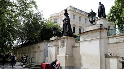 French President Emmanuel Macron lays a wreath at the statue of The Queen Elizabeth the Queen Mother at Carlton Gardens in central London. Reuters