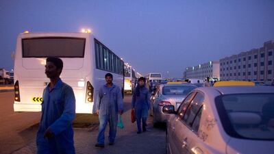 Labourers wait for buses to take them to work after morning prayers outside the Workers Village Labour Camp.