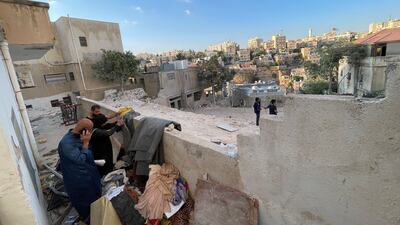 People at the site of a collapsed building in Amman sift through the belongings of their relatives left by demolition crews. Khaled Yacoub Oweis / The National