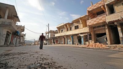 A Syrian man walks past damaged buildings in the town of Ihsim in the southern countryside of Idlib. AFP