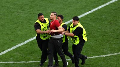 One of several pitch invaders is led away. Getty Images