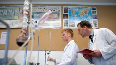 Al Ittihad School chemistry teacher Stephan Lampert watches as Lycee Massignon pupil Gregoire Heim, 16, toils and troubles at diluting an acid during the Chemistry Olympiad 2012 between the two schools.