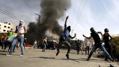 Palestinian protesters throw stones during clashes with Israeli security forces in the West Bank city of Hebron. (Abed Al Hashlamoun / EPA)