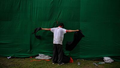 A labourer tears up a cloth as he works near a billboard used during a promotional event at the India Gate monument in New Delhi. Chandan Khanna / AFP