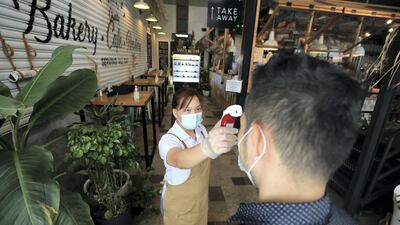 A staff member at a bakery performs a temperature check in Downtown, Dubai. Chris Whiteoak / The National