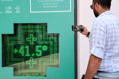 A man takes a photograph of a thermometer display showing a temperature of 41.5 degrees in Paris during a heatwave. AFP