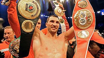 Wladimir Klitschko shows off his belts with brother Vitali, the WBC champion, behind him.