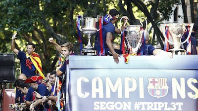 Barcelona’s midfielder Xavi Hernandez and teammate stand on a bus parading through the streets of Barcelona as the team celebrate its victory over Juventus one day after the UEFA Champions League final football on June 7, 2015. Luis Suarez and Neymar scored second-half goals to give Barcelona a 3-1 Champions League final victory over Juventus on June 6, 2015 as the Spaniards became the first team to twice win the European treble. AFP PHOTO/ QUIQUE GARCIA
