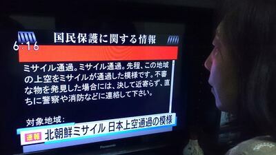 A woman looks at a television news displaying warnings via the "J-alert" system in Tokyo on August 29, 2017, following a North Korean missile test that passed over Japan. Kazuhiro Nogi / AFP