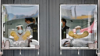 Medical personnel are seen behind their sealed work areas at a swab test screening area for the Covid-19 in New Taipei City. AFP