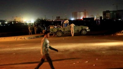 A civilian walks past members of the Sudanese Rapid Support Forces (RSF) are seen near the area where gunmen opened fire outside buildings used by Sudan's National Intelligence and Security Service (NISS) in Khartoum. Reuters