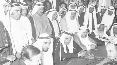 The two men are surrounded by Emirati leaders and the media as they sign the document. National Portrait Gallery via Dubai Media Office