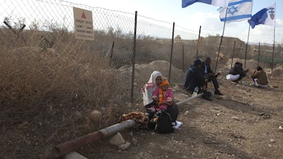 An Ethiopian Orthodox Christian woman sitting with a child by a fence with signs that warn of land mines at the baptismal site known as Qasr Al Yahud, near the West Bank city of Jericho in January 19, 2012.