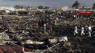 Firefighters and rescue workers walk through the scorched ground. Eduardo Verdugo / AP Photo