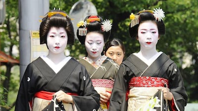 Geishas and their apprentices walk down a street in Kyoto, Japan, on August 1, 2015, to make courtesy visits to their masters. Kyodo