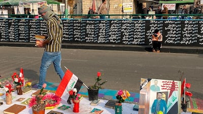 Posters of anti-government protesters who have been killed in demonstrations are displayed by a wall with their names in Tahrir Square during ongoing protests in Baghdad, Iraq. AP