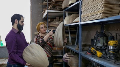 Iranian luthier Fatemeh Moussavi helps musical artist Hamid Khansari pick an instrument at her oud-making workshop in Tehran. AFP