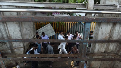 Indian pedestrians walk through the scene of a stampede on a railway bridge in Mumbai. Punit Paranjpe / AFP